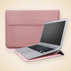 Rosa fodral med krokomönster bredvid en laptop
